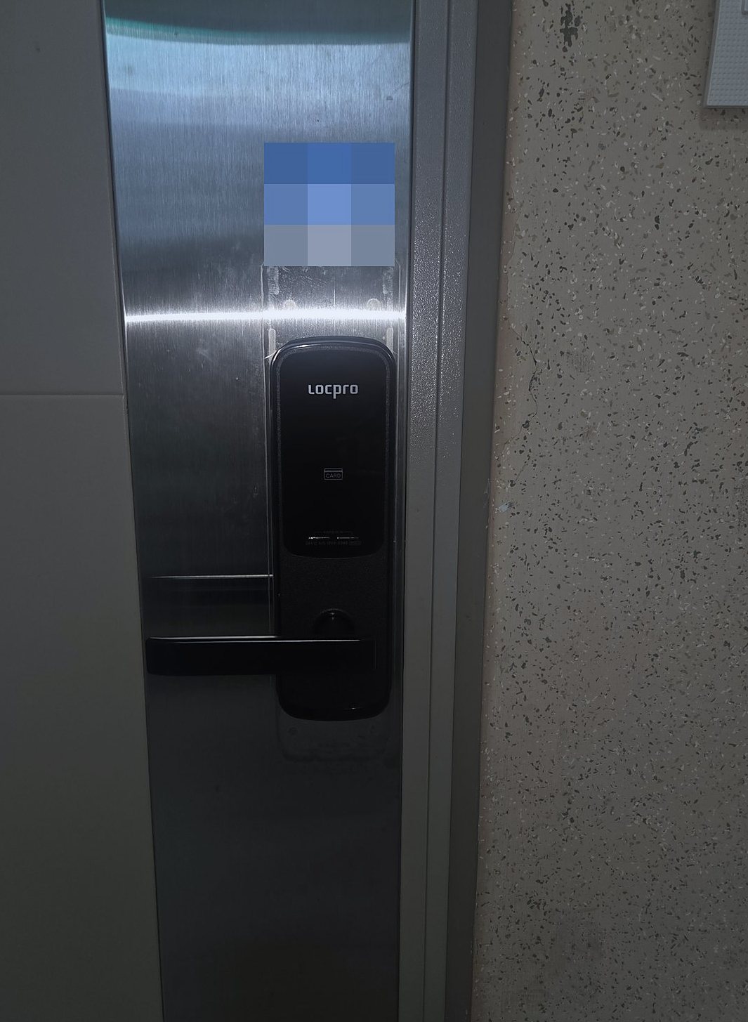 성동구 용답동 출장 — 스테인리스 색 문에 달린 카드 표시의 검은 레버형 도어락과 오른쪽 반점 벽